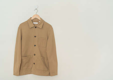 beige suit hanging with wood hanger on wall