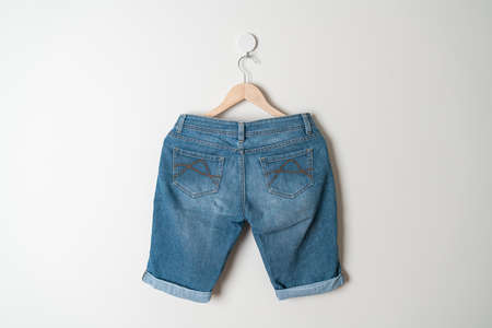 short pants jeans hanging with wood hanger on wallの写真素材