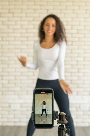 Latin woman influencer created her dancing video by smartphone camera. To share video to social media application.の写真素材