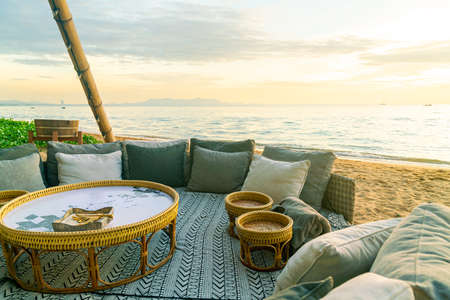 pillows on outdoor patio deck chair on beach with sunset times backgroundの写真素材