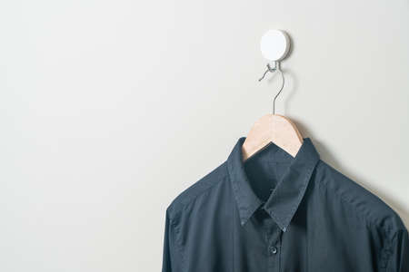 hanging black shirt with wood hanger on wallの写真素材