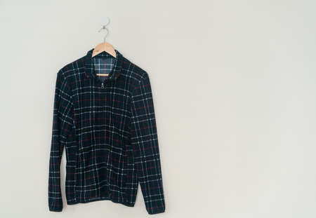 black jacket hanging with wood hanger on wall