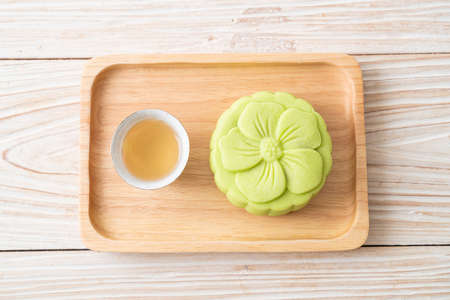 Chinese moon cake green tea flavour with tea on wood plateの写真素材