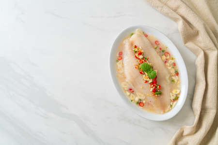 Steamed Fish in Spicy Lemon Sauce on white plateの写真素材