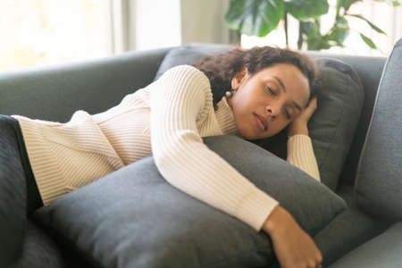 Latin woman sleeping on sofa at homeの写真素材
