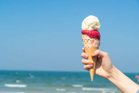 hand holding ice cream cone with blue sky background and copy spaceの写真素材