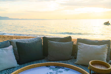 pillows on outdoor patio deck chair on beach with sunset times backgroundの写真素材