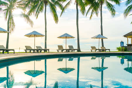 Beautiful luxury umbrella and chair around outdoor swimming pool in hotel and resort with coconut...