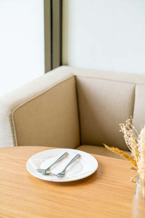 empty white plate with spoon and fork on dinning tableの写真素材