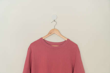 pink t-shirt hanging with wood hanger on wall
