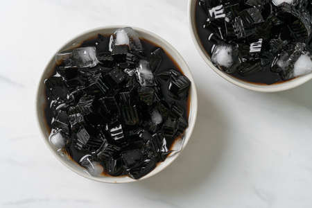 Black grass jelly with ice in bowlの写真素材