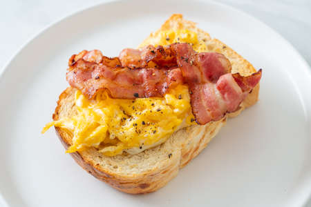 bread toast with scramble egg and bacon on white plate
