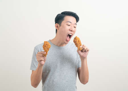 portrait young Asian man with fried chicken on handの写真素材