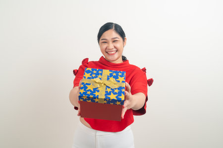 portrait happy Asian woman wearing red shirt with gift box on hand for Christmas festivalの写真素材