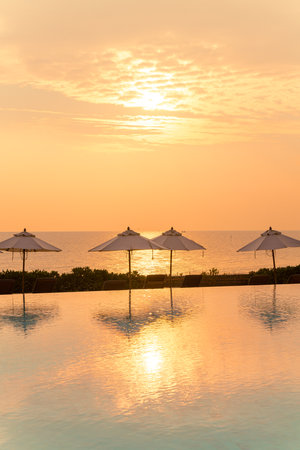 umbrella with bed pool around swimming pool with ocean sea background at sunset or sunrise time -...