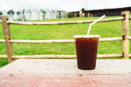 iced americano coffee on wood table with Mountain hill View background