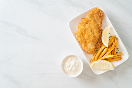 fish and chips - fried fish fillet with potatoes chips and lemon on white plateの写真素材