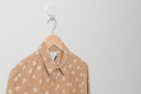 hanging beige shirt with wood hanger on wallの写真素材