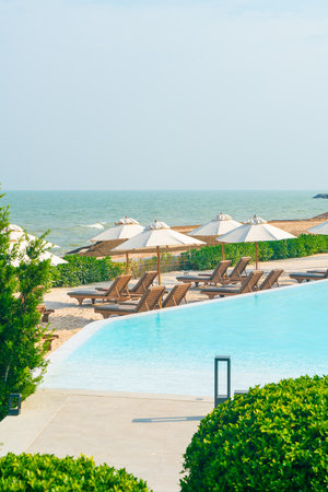 umbrella with bed pool around swimming pool with ocean sea background - holiday and vacation concept