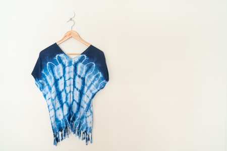 tie dye shirt hanging with wood hanger on wallの写真素材