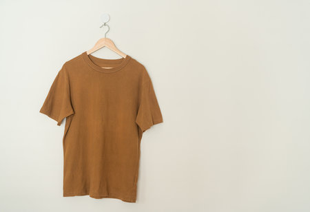brown t-shirt hanging with wood hanger on wallの写真素材