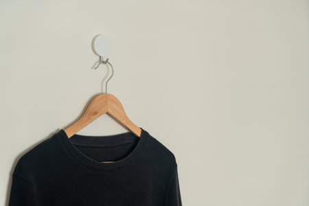 black sweater hanging with wood hanger on wallの写真素材