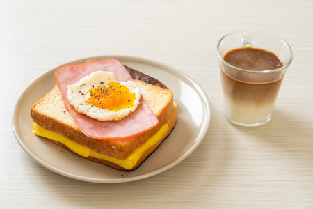 homemade bread toasted cheese topped ham and fried egg with pork sausage and coffee for breakfastの写真素材