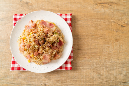 fried rice with bacon ham and black peppers on white plateの写真素材