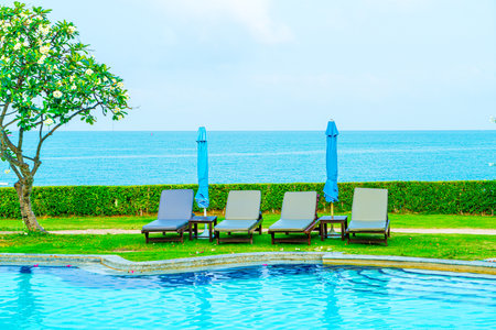 chair pool and umbrella around swimming pool with ocean sea backgroundの写真素材