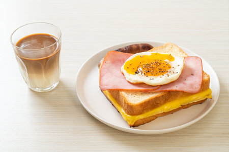 homemade bread toasted cheese topped ham and fried egg with pork sausage and coffee for breakfastの写真素材