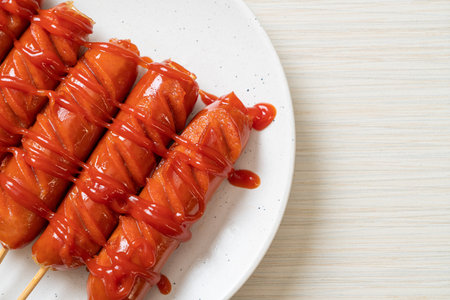 fried sausage skewer with ketchup on white plateの写真素材