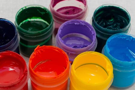Colorful paints in plastic containers on white background