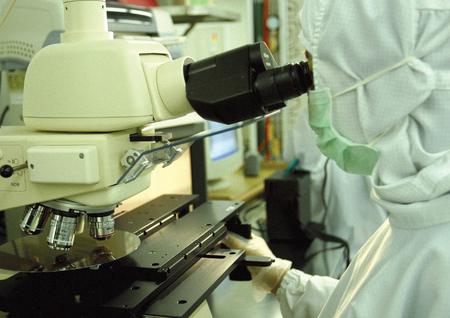 Side profile of a scientist in front of a microscope