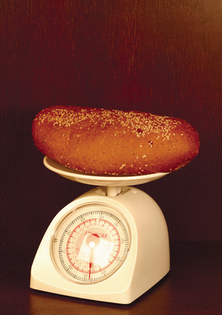 Close-up of a loaf of brown bread on a kitchen scaleの写真素材