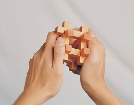 Close-up of a wooden puzzle in a man's handsの写真素材