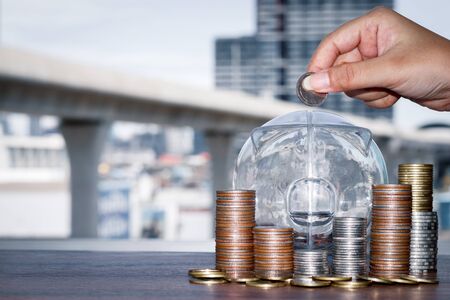 Woman's hand Putting money into the piggy bank. Concept of saving money and business investment in the future.の写真素材