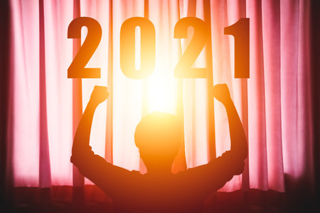 Silhouette man raise hands welcoming the year 2021with sun shines through the curtains background, Concept New year success.の写真素材