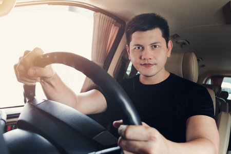 Enjoying his drive. Handsome young man in Black t-shirt wear smiling while driving a status car, Vintage tone photo.の写真素材