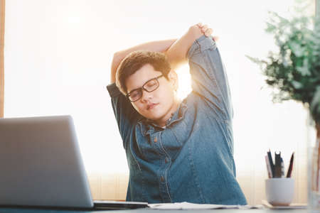 young businessman exercises stretching the muscles at the desk at work, Relax from hard work.の写真素材