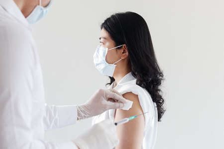 Doctor giving Covid vaccine to Asian womenの写真素材