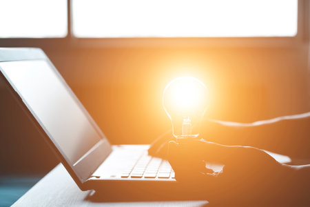 Hand holding a light bulb and working on a laptop computer, Concept of inspirational ideas creativity and technological innovation of the future.の写真素材
