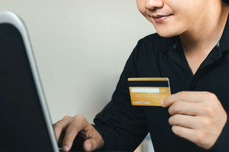 Online Shopping concept. young man is typing an online payment number from his credit card to his laptop computer.の写真素材
