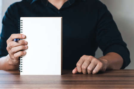 Businessman displays a notebook with a copy area with pen, note taking business and finance goals,...