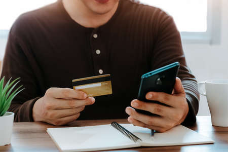 Young man using smart phone and credit card for shopping online in coffee shop cafe.の写真素材