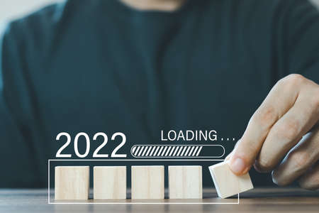 male hand hand putting wood cube in progress bar for Loading 2022 years. happy new years 2022.の写真素材