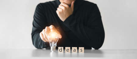 young man touched lightbulb, wood block with Word Ideas, concepts new ideas inspiration and innovation.の写真素材