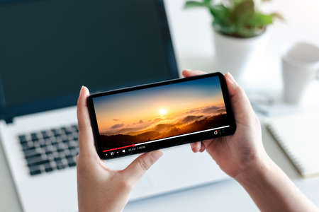 Online movie stream with smartphone. Young man watching film on mobile phone with imaginary video...