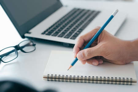 Businessman taking notes Summarize the meeting online with laptop, working alone, sitting at your...