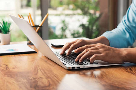 young man using laptop computer and mobile phone When looking for financial information in business,...