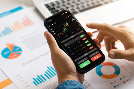 Businessmen work with stock market investments using smartphone to analyze trading data. smartphone with stock exchange graph on screen. Financial stock market.の写真素材